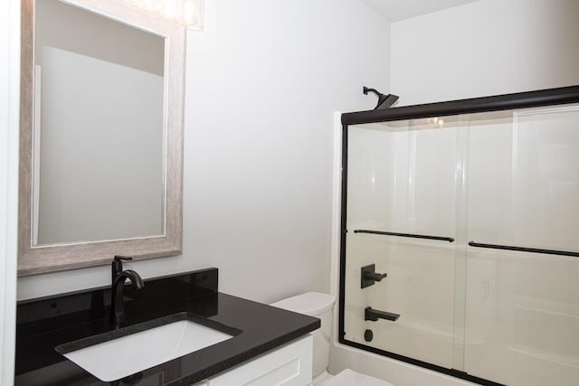 bathroom with toilet, shower / bath combination with glass door, and vanity