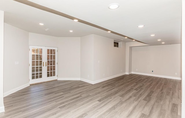 spare room with light wood finished floors, french doors, baseboards, and recessed lighting