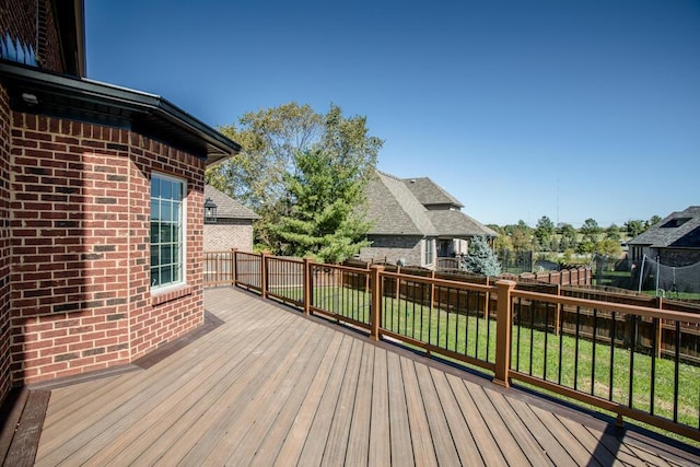 wooden terrace featuring a yard and fence