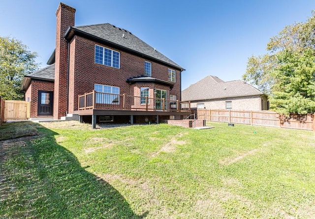 rear view of house with brick siding, a yard, a chimney, a fenced backyard, and a wooden deck