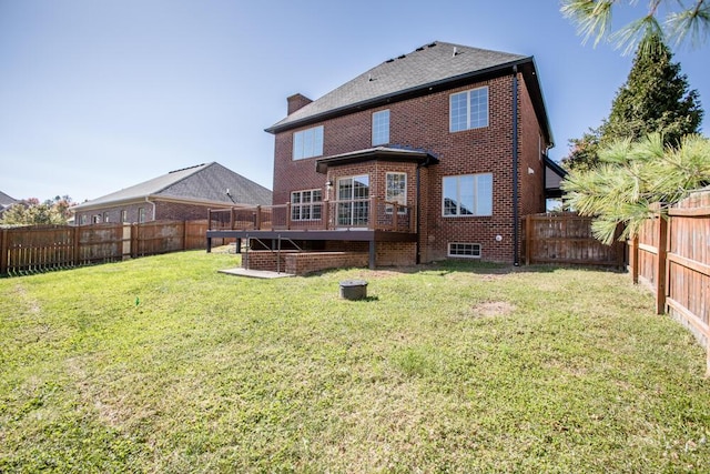 rear view of house featuring brick siding, a lawn, a chimney, and a fenced backyard