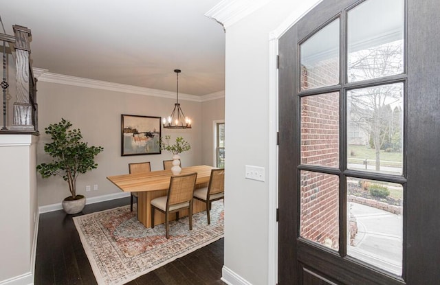 dining area with a notable chandelier, dark wood-type flooring, baseboards, and crown molding