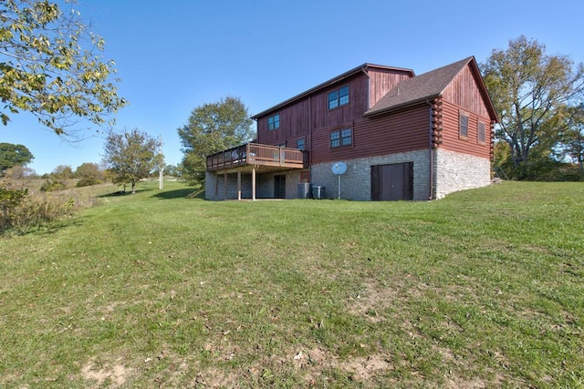 rear view of property featuring a wooden deck and a lawn