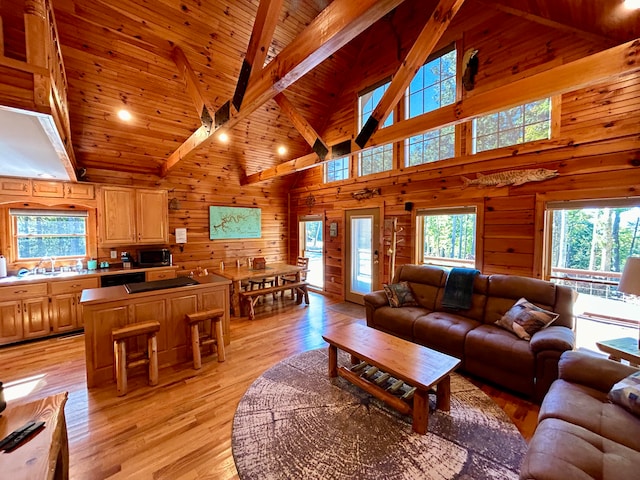 living room with light wood-type flooring, high vaulted ceiling, and wood walls