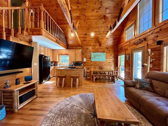 living room with beamed ceiling, light hardwood / wood-style flooring, wood walls, and high vaulted ceiling