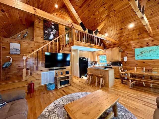 living room with light wood-type flooring, high vaulted ceiling, wood walls, and beamed ceiling