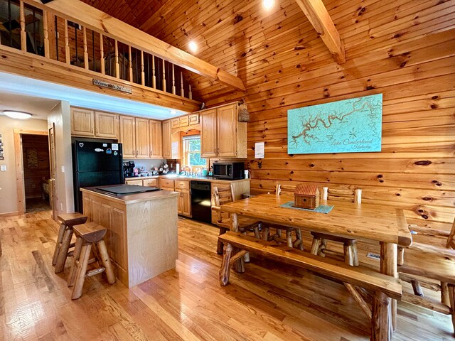 kitchen with a kitchen island, black appliances, beam ceiling, and light hardwood / wood-style floors