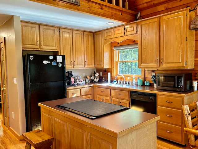 kitchen with a kitchen island, light wood-type flooring, sink, and black appliances