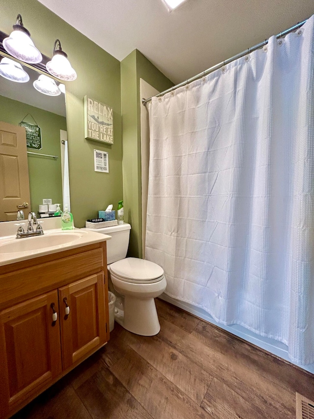 bathroom featuring vanity, wood-type flooring, a shower with curtain, a notable chandelier, and toilet