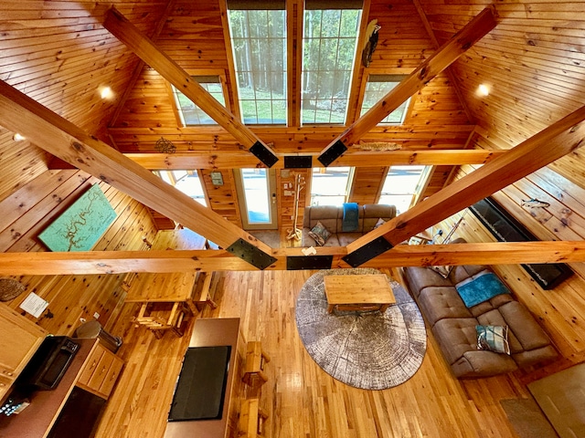 unfurnished living room featuring wood walls, light hardwood / wood-style floors, and high vaulted ceiling