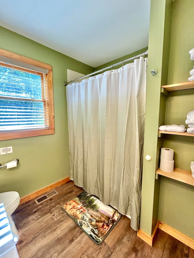 bathroom featuring curtained shower, wood-type flooring, and toilet