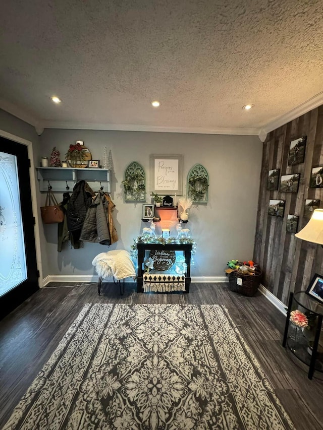 living area featuring dark hardwood / wood-style floors, a textured ceiling, wooden walls, and ornamental molding