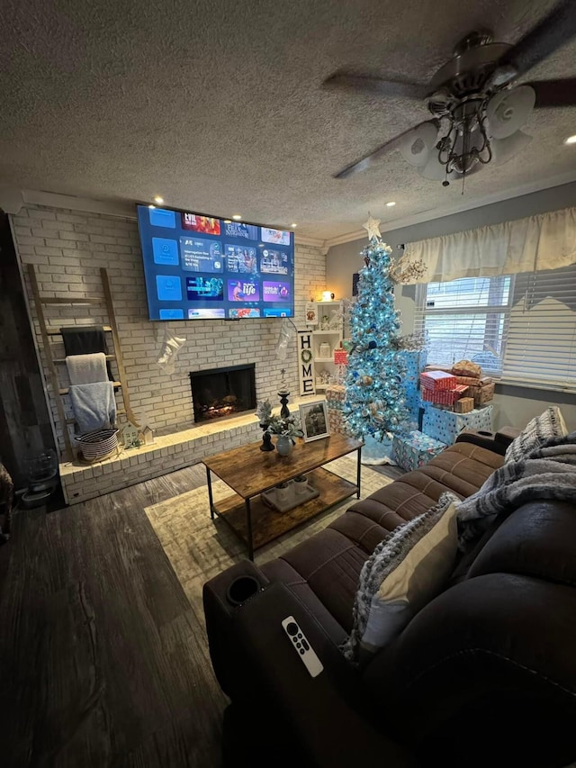 living room with a textured ceiling, hardwood / wood-style flooring, ornamental molding, and a fireplace