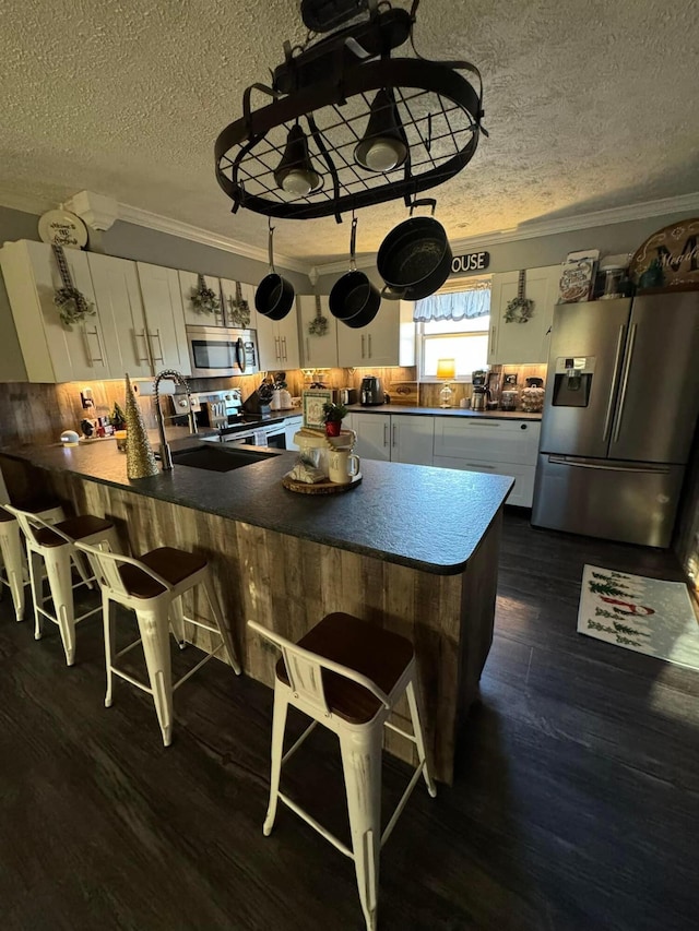 kitchen with dark wood-type flooring, white cabinets, a textured ceiling, and appliances with stainless steel finishes