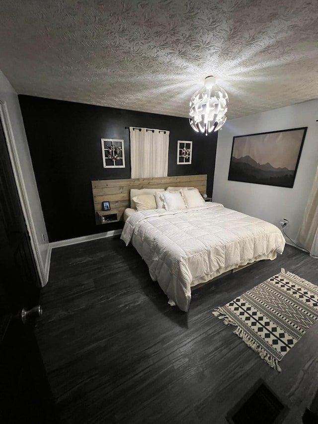 bedroom with dark wood-type flooring, an inviting chandelier, and a textured ceiling