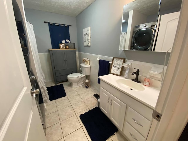 bathroom featuring toilet, tile patterned floors, a textured ceiling, vanity, and washer / dryer