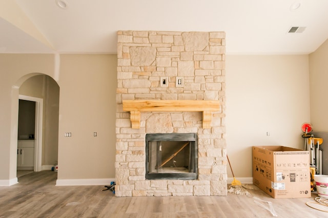 unfurnished living room featuring hardwood / wood-style floors and a stone fireplace