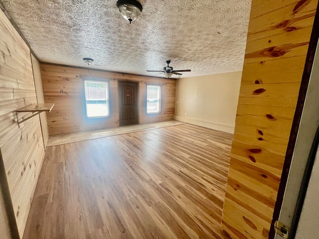 interior space featuring ceiling fan, hardwood / wood-style flooring, wooden walls, and a textured ceiling