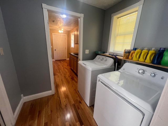 laundry room featuring a textured ceiling, light hardwood / wood-style flooring, and washer and dryer