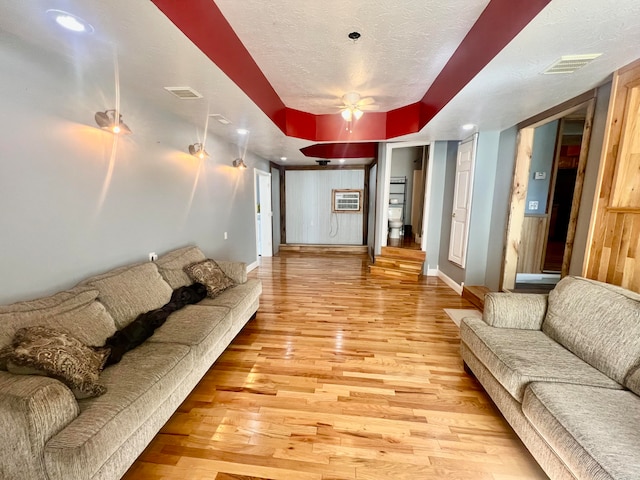 living room featuring ceiling fan, a textured ceiling, and light hardwood / wood-style flooring