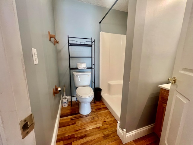 bathroom featuring hardwood / wood-style floors, vanity, toilet, a shower, and a textured ceiling