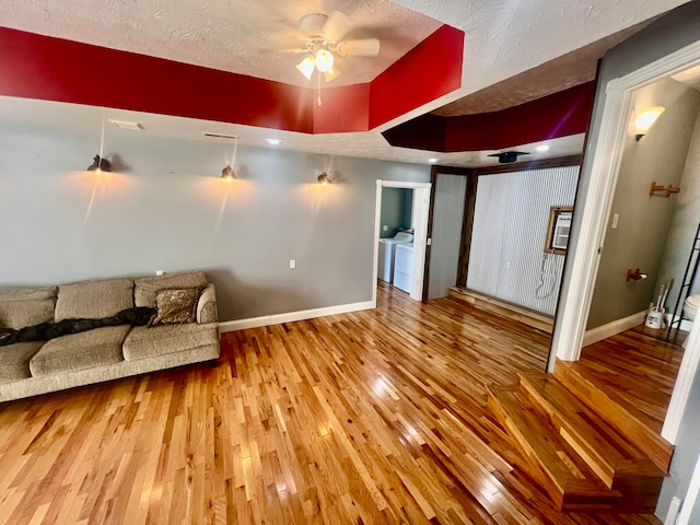 living room featuring ceiling fan, hardwood / wood-style flooring, a textured ceiling, and washer and clothes dryer