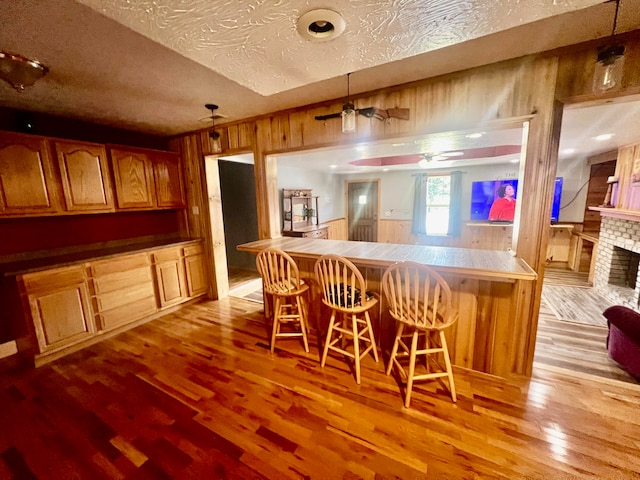 kitchen with a textured ceiling, light wood-type flooring, and a breakfast bar