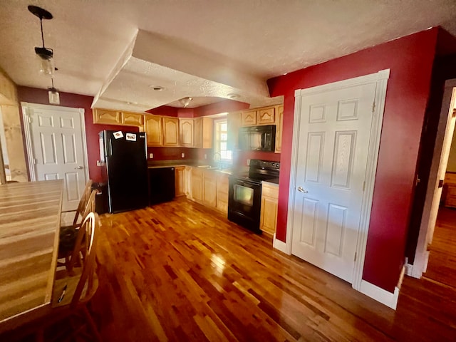 kitchen with black appliances, light brown cabinets, sink, dark hardwood / wood-style flooring, and a textured ceiling