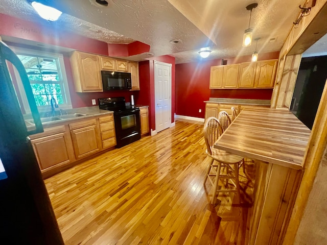 kitchen with light hardwood / wood-style floors, pendant lighting, sink, black appliances, and a textured ceiling