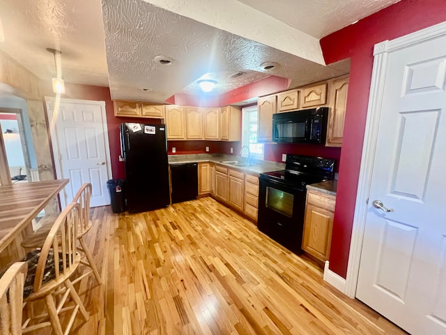 kitchen featuring light brown cabinets, sink, a textured ceiling, light hardwood / wood-style flooring, and black appliances