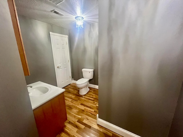 bathroom featuring a textured ceiling, wood-type flooring, vanity, and toilet