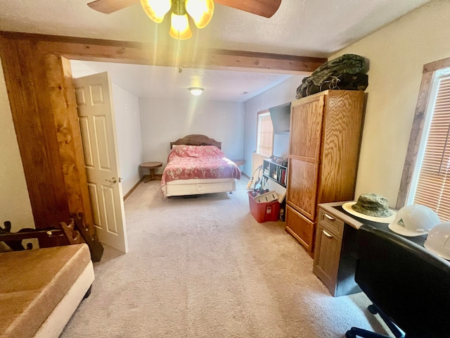 bedroom featuring light carpet, beamed ceiling, ceiling fan, and a textured ceiling