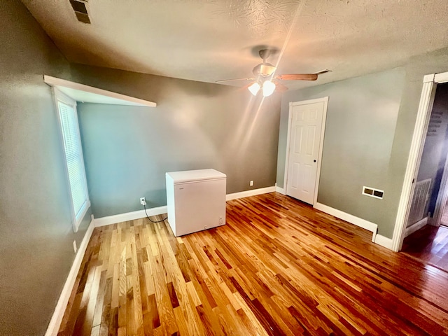 unfurnished room featuring a textured ceiling, a healthy amount of sunlight, light wood-type flooring, and ceiling fan