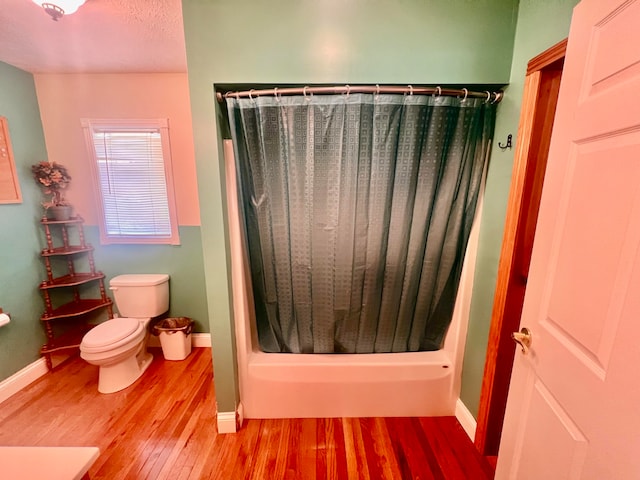 bathroom featuring hardwood / wood-style flooring, shower / bath combo with shower curtain, and toilet