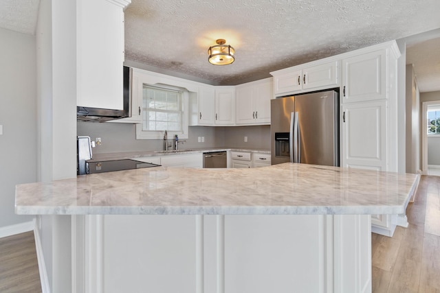 kitchen with white cabinets, light wood-type flooring, a textured ceiling, and stainless steel appliances
