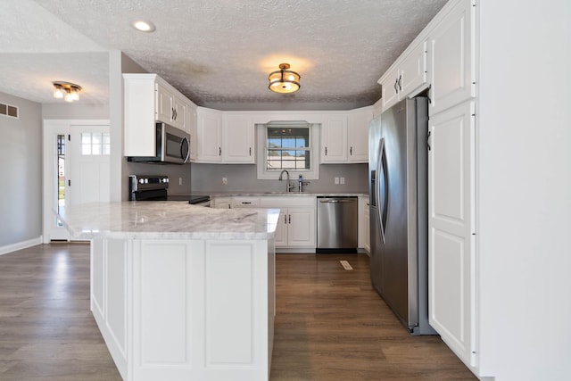 kitchen with a peninsula, dark wood finished floors, white cabinets, and stainless steel appliances