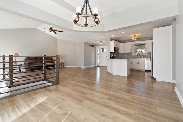 living room with light wood-style floors, ceiling fan with notable chandelier, and baseboards