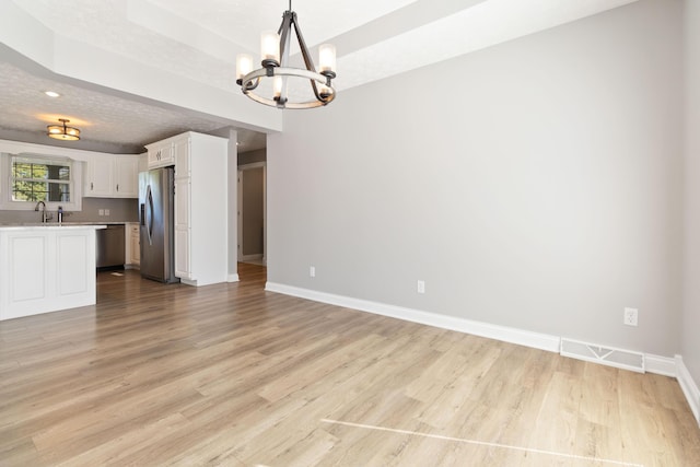interior space featuring light wood-style floors, visible vents, a chandelier, a sink, and baseboards