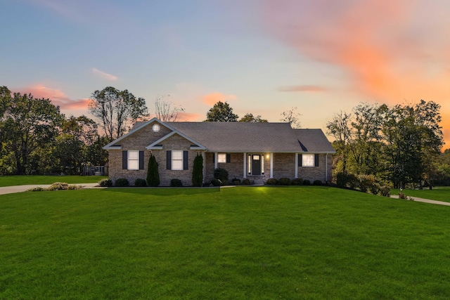 ranch-style home featuring a yard and brick siding