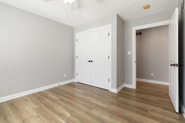 unfurnished bedroom featuring light wood-style floors, a closet, baseboards, and visible vents