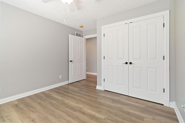unfurnished bedroom with light wood-style floors, a closet, a ceiling fan, visible vents, and baseboards