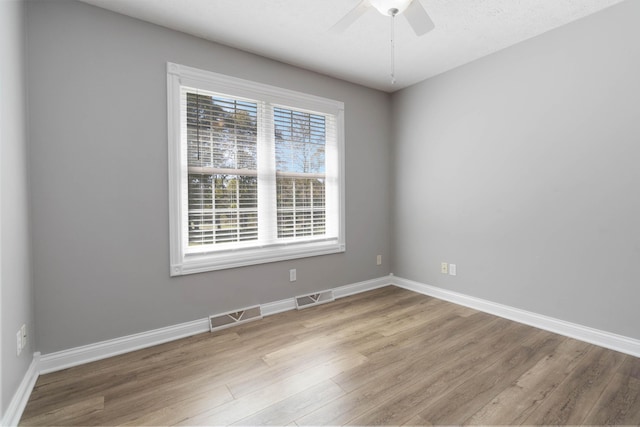 empty room featuring light wood-style flooring, baseboards, a ceiling fan, and visible vents