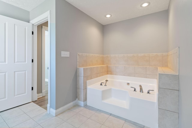 bathroom featuring baseboards, recessed lighting, tile patterned floors, a textured ceiling, and a garden tub