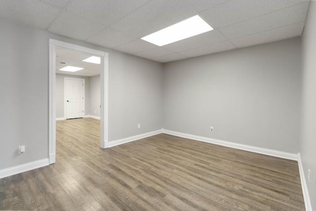 empty room with wood finished floors, baseboards, and a drop ceiling