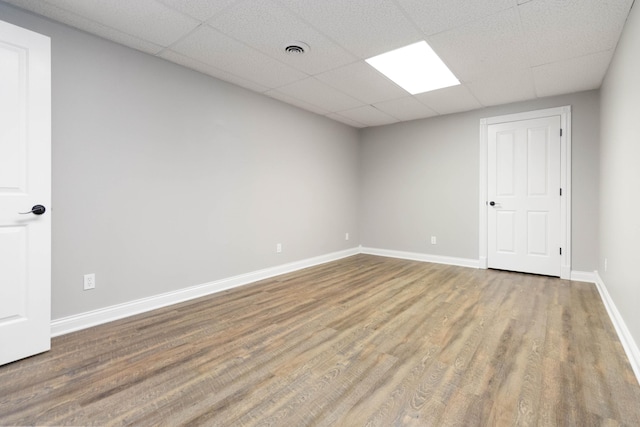 empty room with visible vents, baseboards, a drop ceiling, and wood finished floors