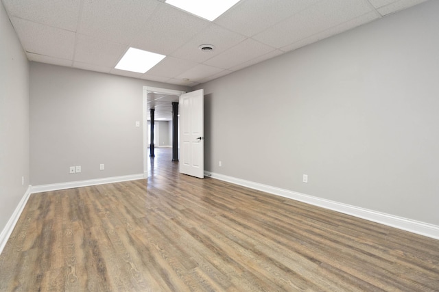empty room featuring visible vents, a drop ceiling, baseboards, and wood finished floors