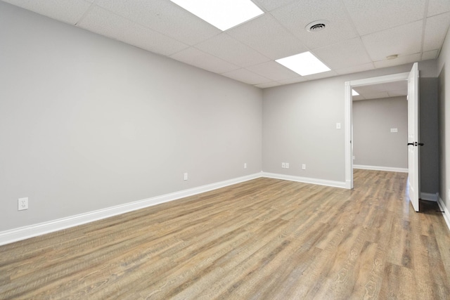 spare room featuring visible vents, baseboards, a drop ceiling, and light wood-style floors