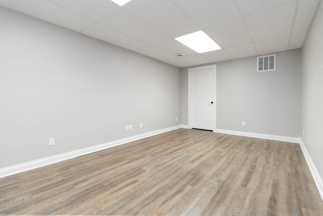 empty room with visible vents, baseboards, a paneled ceiling, and wood finished floors