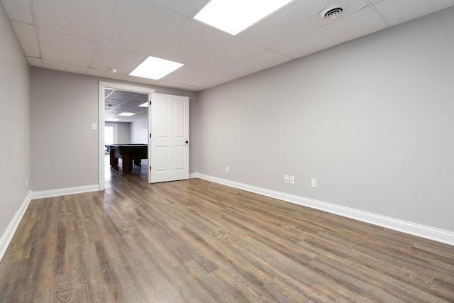 interior space with a drop ceiling, visible vents, baseboards, and wood finished floors