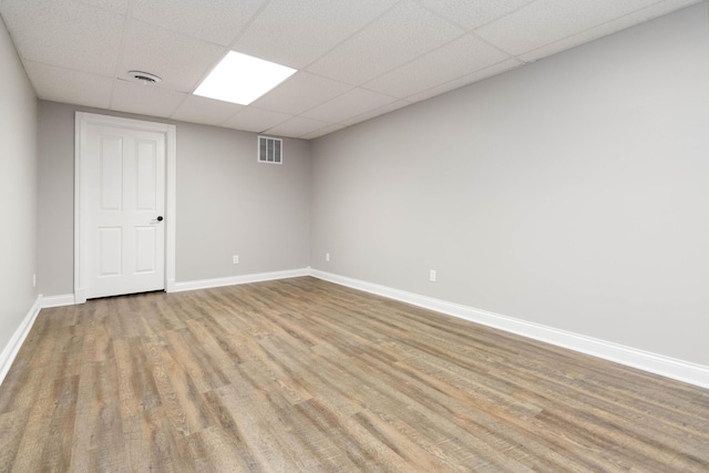 empty room featuring visible vents, baseboards, a paneled ceiling, and wood finished floors